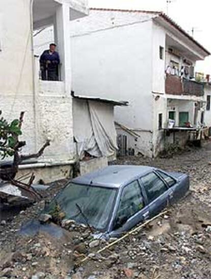 Un vecino de Rincón de la Victoria contempla, ayer, un coche atrapado por la riada.