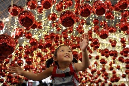 Una niña juega con la decoración navideña en un centro comercial de Bangkok (Tailanda), el 4 de diciembre de 2018.