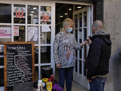 Una empleada de un bar de Sant Just Desvern (Barcelona) comprueba el certificado covid de un cliente en la entrada del local el primer día de su vigencia.