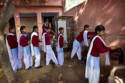 Un grupo de niñas se lava las manos antes de tomar las pastillas del programa de desparasitación.
