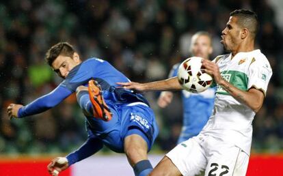 Velázquez, del Getafe, despeja un balón ante Jonathas, del Elche.