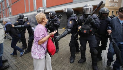 Un dona intenta dialogar amb antidisturbis a l'escola Mediterrània de la Barceloneta.