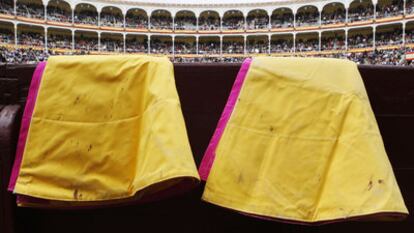 Dos capotes colgados de la barrera de la plaza de Las Ventas.
