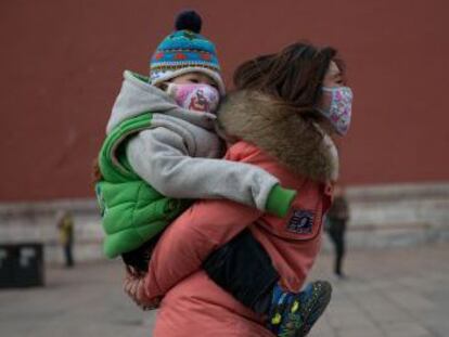 Una mujer y un bebé con máscaras en Pekín.