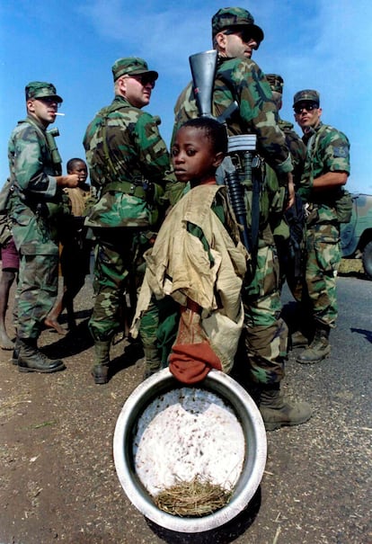 Un niño ruandés espera para recoger agua frente a un grupo de soldados de Estados Unidos en el campo de refugiados de Kibumba (Tanzania), el 2 de agosto de 1994.