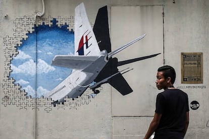 Um homem caminha ao lado de um mural em homenagem ao voo MH370 em Shah Alam, nos arredores de Kuala Lumpur (Malásia), em março de 2015.