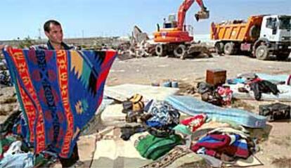 Un inmigrante guardaba ayer sus pertenencias mientras una excavadora derribaba las chabolas que habitaban en El Ejido.