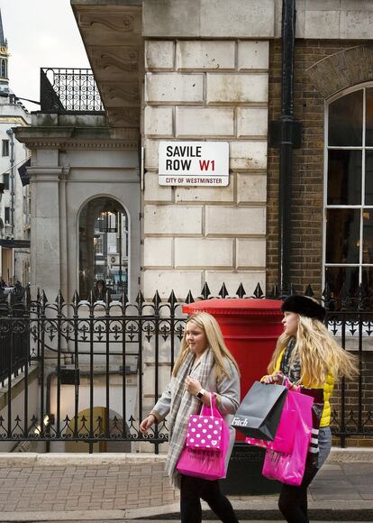 Dos jóvenes pasean frente el cartel de la calle Savile Row, en Londres.