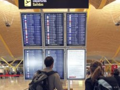 Unos viajeros consultan vuelos de salida en uno de los paneles de la T-4 del aeropuerto de Barajas de Madrid.