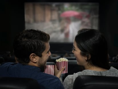 Una pareja consume palomitas en una sala de cine.