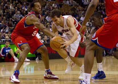 El jugador de Toronto Raptors, José Calderón, en el centro, lleva el balón entre los jugadores de Philadelphia Andre Iguodala (izquierda) y Jrue Holiday (derecha).