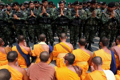 Un grupo de monjes budistas del templo de Dhammakaya se enfrentan a soldados tailandeses ubicados en una puerta de dicha edificación, en la provincia de Pathum Thani (Tailandia).