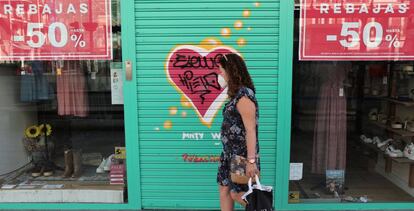 Una viandante pasa por delante de una tienda de ropa cerrada durante la temporada de rebajas de verano, este lunes, en Madrid