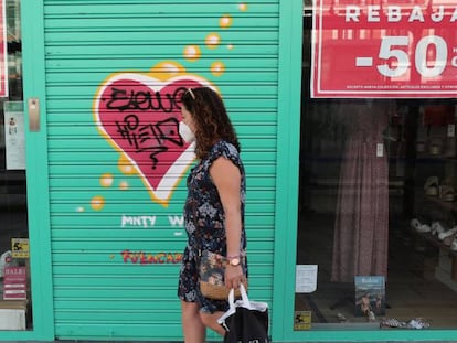 Una viandante pasa por delante de una tienda de ropa cerrada durante la temporada de rebajas de verano, este lunes, en Madrid