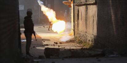 Un policía indio observa como estalla una bomba de humo cerca de un manifestante, en Srinagar.