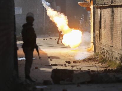 Un policía indio observa como estalla una bomba de humo cerca de un manifestante, en Srinagar.