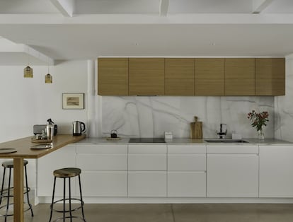 En la cocina, los armarios —lacados en blanco o acabados en bambú— y la mesa alta son de la carpintería Klaus Speis. La encimera es de mármol blanco; el grifo, de Galindo; el pequeño dibujo, de Elena Molinari, y los taburetes, de Noak Room.