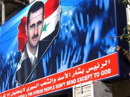 Jóvenes sirias pasan delante de un cartel propagandístico de Bachar el Asad, en Damasco.