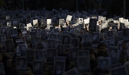 Varias personas sostienen pancartas con retratos de las víctimas del ataque terrorista contra la Asociación Mutual Israelita Argentina (AMIA) durante su 23º aniversario, en Buenos Aires.