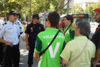 Un agente francés y un policía nacional atienden a voluntarios de la JMJ.