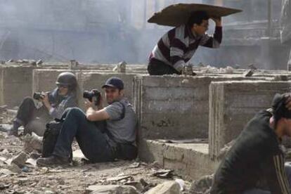 Dos fotógrafos extranjeros se resguardan de una batalla de piedras entre manifestantes a favor y en contra de Mubarak en El Cairo.