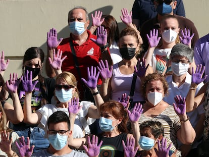 Personas con las manos moradas guardan un minuto de silencio en el Ayuntamiento de Málaga tras un asesinato machista el pasado 16 de julio.