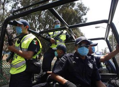 Agentes de policía patrullan las calles de México DF protegidos por mascarillas.