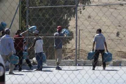 Un grupo de porteadores lanza mercancías por encima de la verja del paso fronterizo de Ceuta.