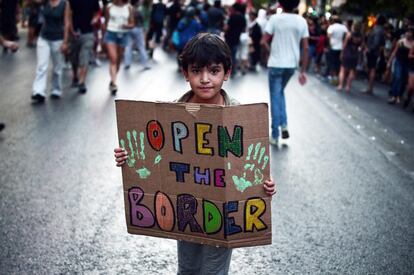 Un niño sujeta una pancarta que dice 'Abrid la frontera', durante una manifestación en apoyo a los refugiados frente al Ayuntamiento de Atenas (Grecia). 