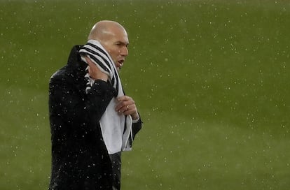 El entrenador del Real Madrid, Zinedine Zidane, se seca la cabeza de la lluvia caída al final del partido. 
