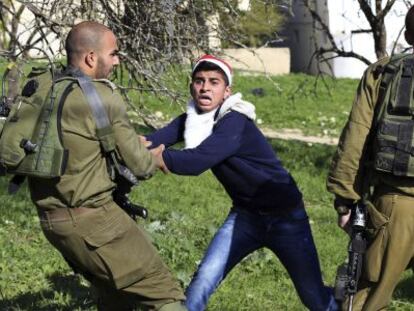 Un manifestant palestí amb barret i barba de Pare Noel (centre) s'enfronta a un soldat israelià en una protesta prop de Nablus.