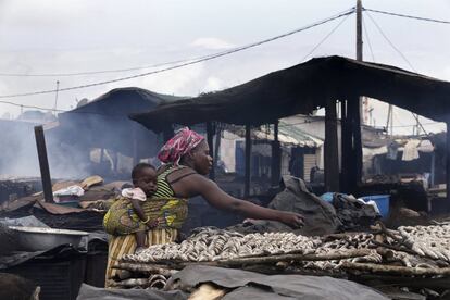 Una mujer prepara pescado para ser ahumado en un mercado de Abiyán, Costa de Marfil.