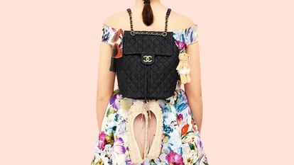 Minimochila con solapa superior y cierre dorado de Chanel. En los laterales, pompón de cuero azul de Swarovski, gafas en pasta roja de Dolce & Gabbana, llavero de osita de Airfield y bailarinas con bordado de flores de Pretty Ballerinas. El vestido de seda estampada es de Coosy. 