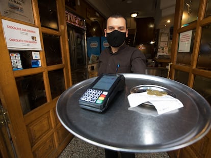 Eduardo, camarero del bar Cantalejo en Madrid, muestra la propina que ha dejado un cliente.