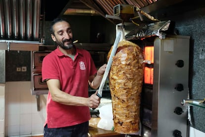 Zaza corta el pincho de carne de 'kebab' en su restaurante Sumer, en Madrid.