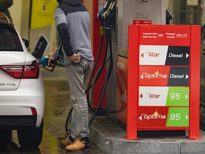 Una persona echa gasolina del surtidor de una gasolinera.