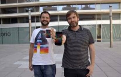 Los jóvenes aragoneses de la empresa emedia, Abraham Casanova (d) y Víctor Mógica (i), aficionados a disfrutar al máximo de las festividades patronales y de "cuántas más mejor", muestran en sus móviles la aplicación "SonFiestas", que han desarrollado y que salió al mercado el pasado 20 de junio, registra ya más de 2.000 descargas gratuitas en apenas quince días.