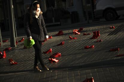 Una mujer camina entre docenas de zapatos pintados de rojo colocados en el suelo para protestar contra la violencia contra las mujeres en Bruselas. Este lunes se celebra el Día Internacional contra la Violencia de Género.