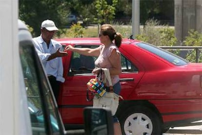 Una mujer entrega unas monedas a un <b><i>gorrilla</b></i> en la calle San Lorenzo, junto al hospital Ramón y Cajal.