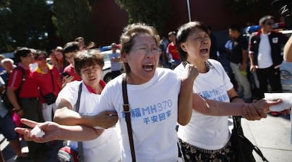Familiares de los pasajeros del vuelo MH370 de Malaysia Airlines lloran durante una ceremonia en Pekín cuando se cumplen seis meses de la desaparición del avión.