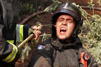 Un bombero se refresca durante la extinción de un incendio forestal en la provincia de Cauquenes, región del Bio Bio (Chile). Unos 1.200 miembros de las Fuerzas Armadas y más de 500 bomberos se han sumado a combatir las llamas que afectan las regiones sureñas chilenas de O'Higgins y El Maule.