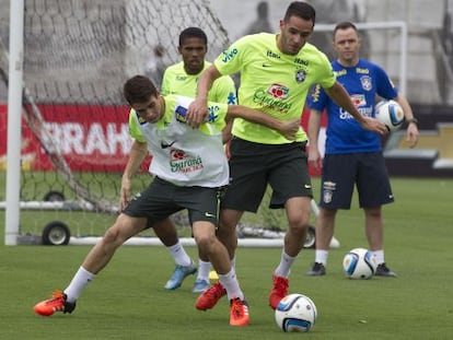 Oscar e Renato Augusto disputam a bola durante treino.