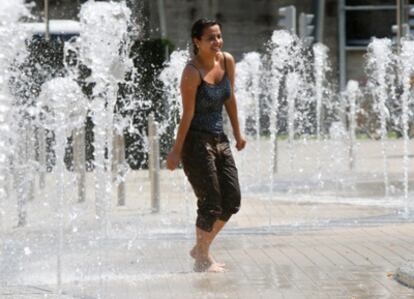 Una joven se refresca en unas fuentes del parque de Abandoibarra en Bilbao.