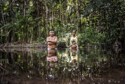 Um casal com seu bebê no rio, a única fonte de água.