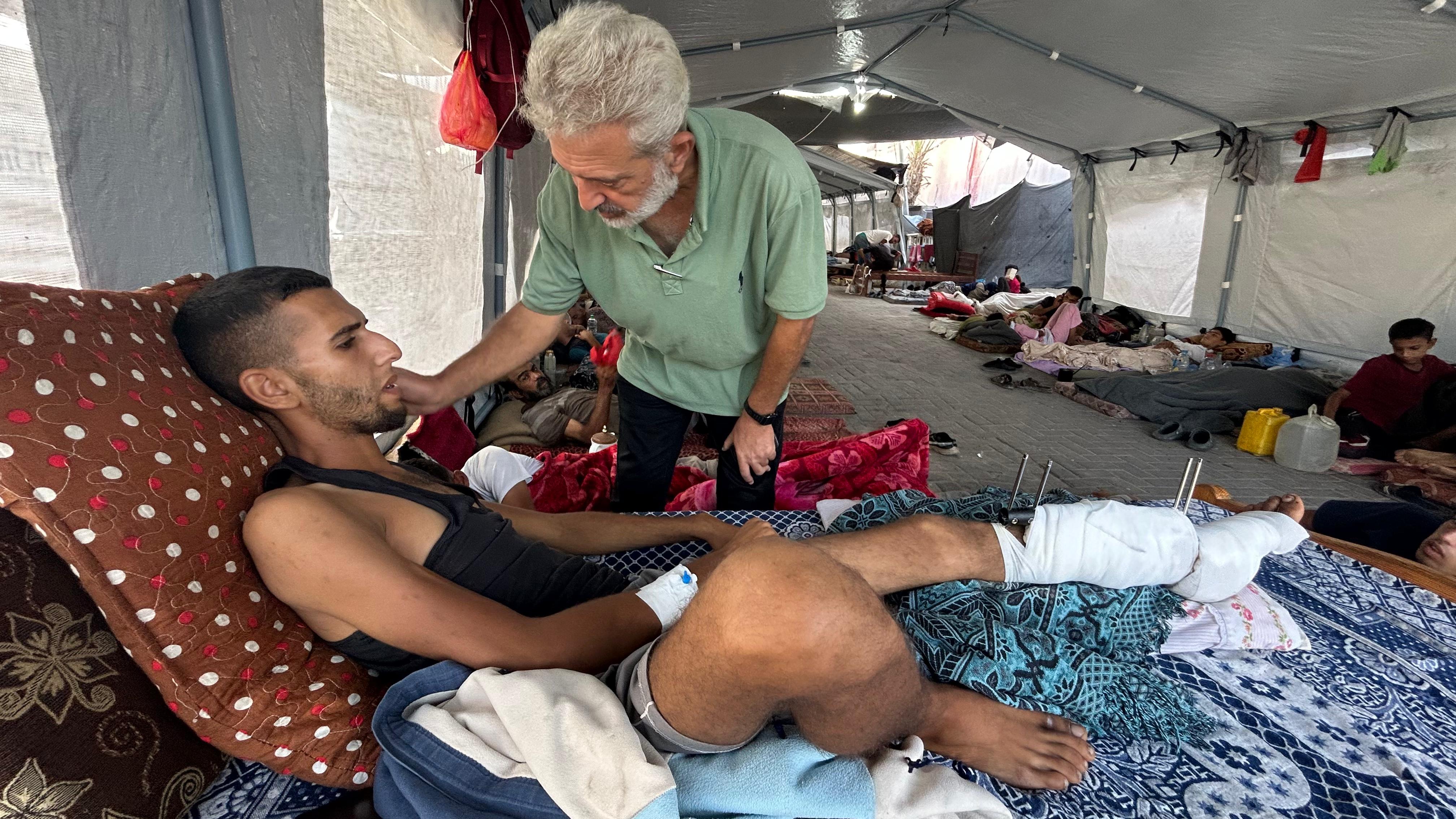 Abdel Rahman Abu Shawish, al que tienen que amputarle el pie, yace en un colchón traído de su casa junto a su padre en el hospital Nasser en Jan Yunis (Gaza).