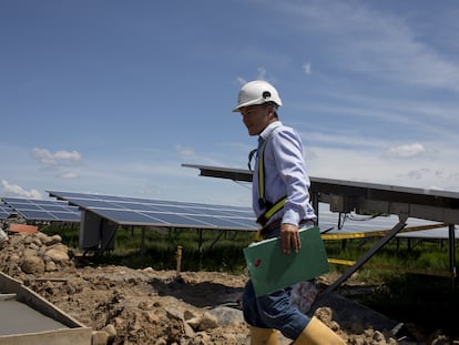 Un empleado pasa junto a paneles solares durante la construcción de la planta solar Ecopetrol SA, operada por AES Colombia.