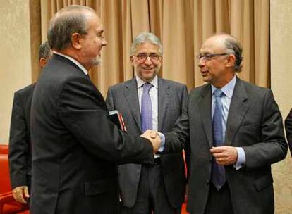 Pedro Solbes saluda al portavoz de Economía del PP, Cristóbal Montoro, en el Congreso.