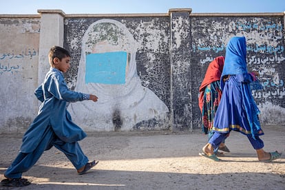 Dos niños en Afganistán pasan junto a un mural dañado en el que aparece una niña afgana. El texto de la pared (a la derecha) habla de las virtudes de la educación de las niñas.  Según datos de Unicef de 2021, el 28% de las afganas entre 15 y 49 años se habían casado antes de cumplir los 18. Los talibanes decretaron a finales de ese año que las mujeres no debían ser consideradas "propiedad" y que tenían que consentir el matrimonio, pero organizaciones de derechos humanos denuncian que los matrimonios infantiles se han disparado debido a la pobreza y la falta de oportunidades.