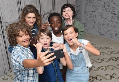 Los más jóvenes del reparto de Stranger Things (Gaten Matarazzo, Natalia Dyer, Noah Schnapp, Caleb McLaughlin, Finn Wolfhard y Millie Bobby Brown) y un móvil.