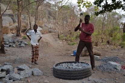 El hijo mayor de la familia Madougou, de 15 años, pica granito para convertirlo en grava dentro de un neumático de camión, la única protección de que dispone. En la cantera de Tchachegou en el centro de Benín. 